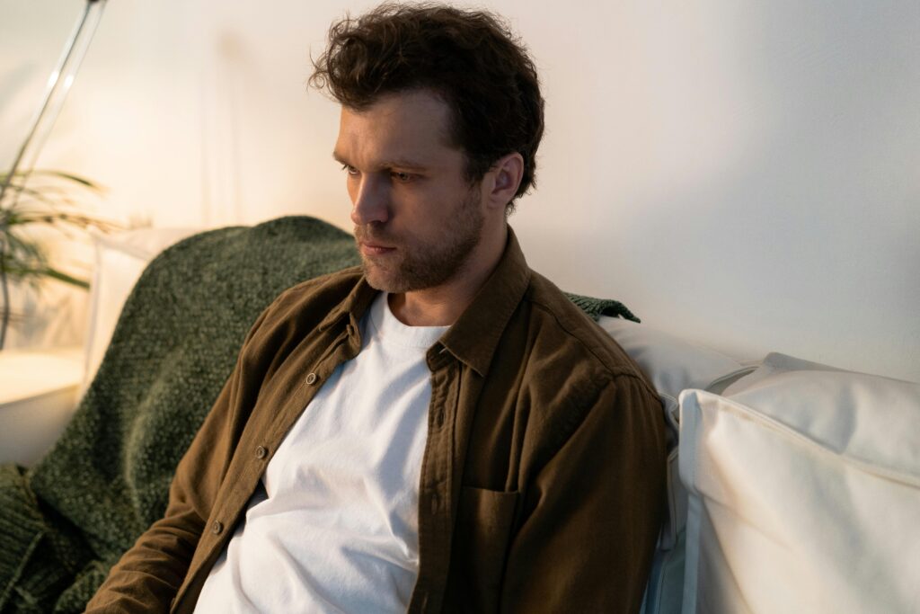 Person sitting quietly on a couch with low energy, reflecting the feeling of being unmotivated
