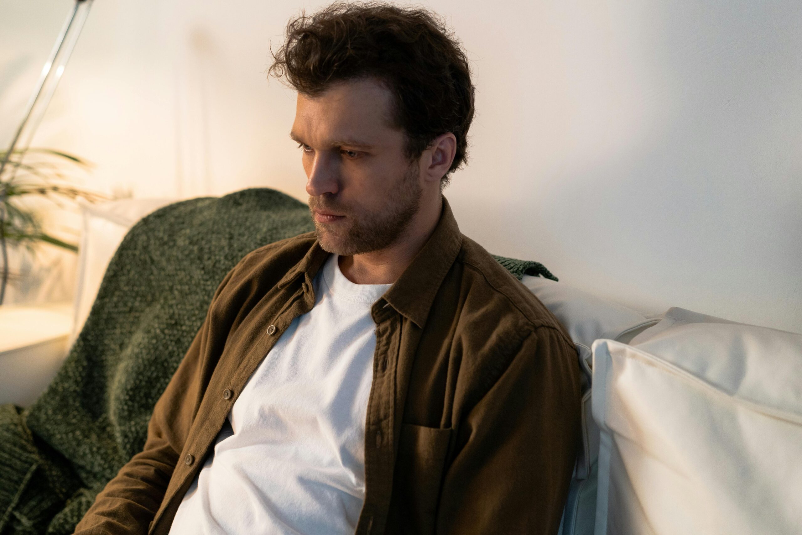 Person sitting quietly on a couch with low energy, reflecting the feeling of being unmotivated