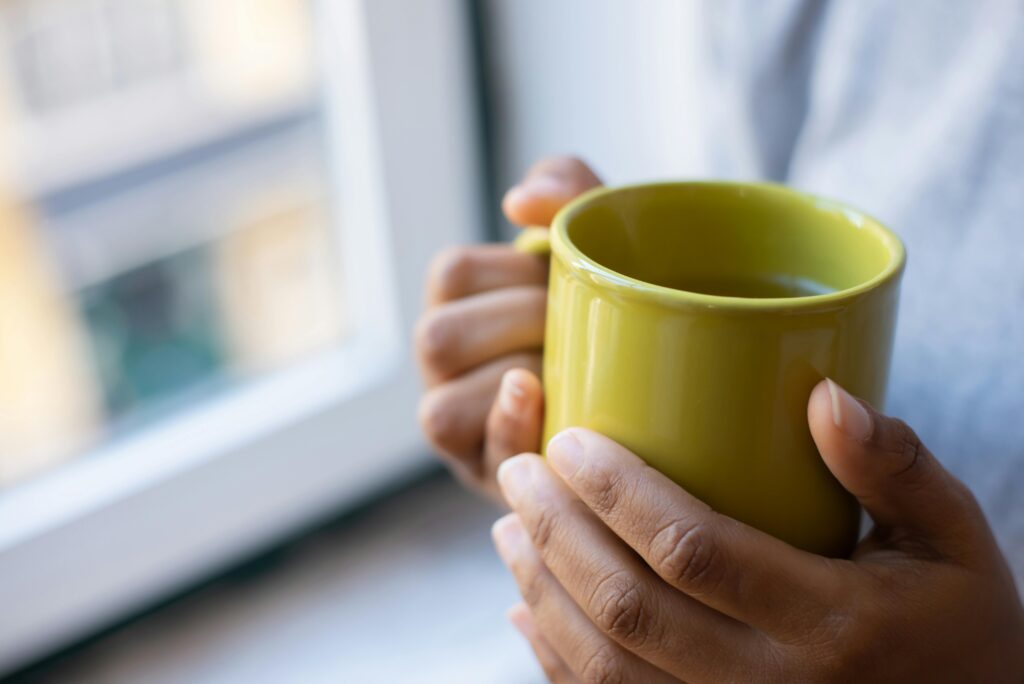 Hands holding a warm mug in soft morning light, capturing a quiet daily happiness ritual.