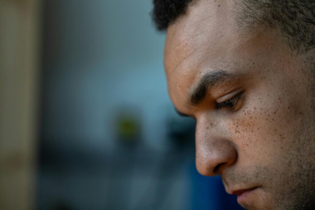 Close‑up of a person in soft natural light, pausing in quiet emotional reflection to regain self‑control.