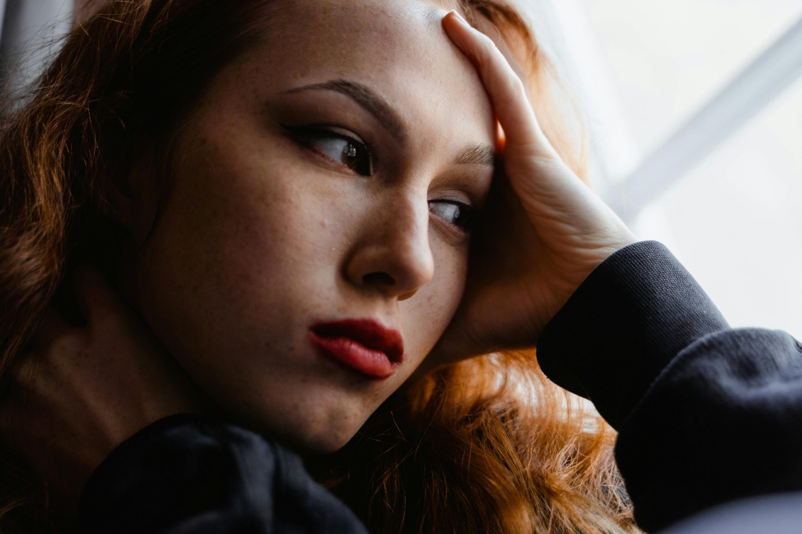 Person sitting by a window in soft natural light, pausing in quiet reflection to regulate their emotions.